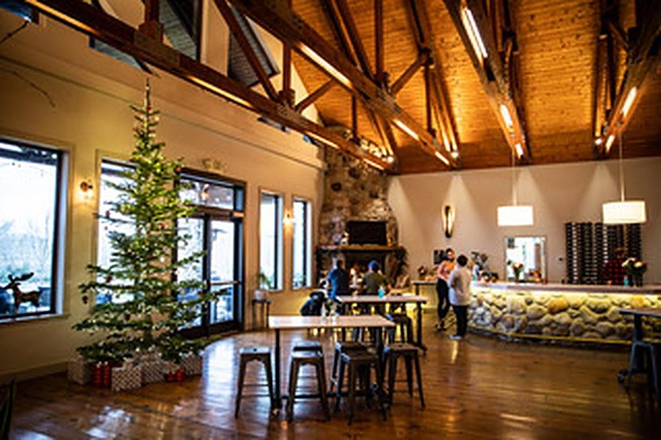 A winery tasting room with a timber ceiling, a stone-front bar and a Christmas tree by the windows.